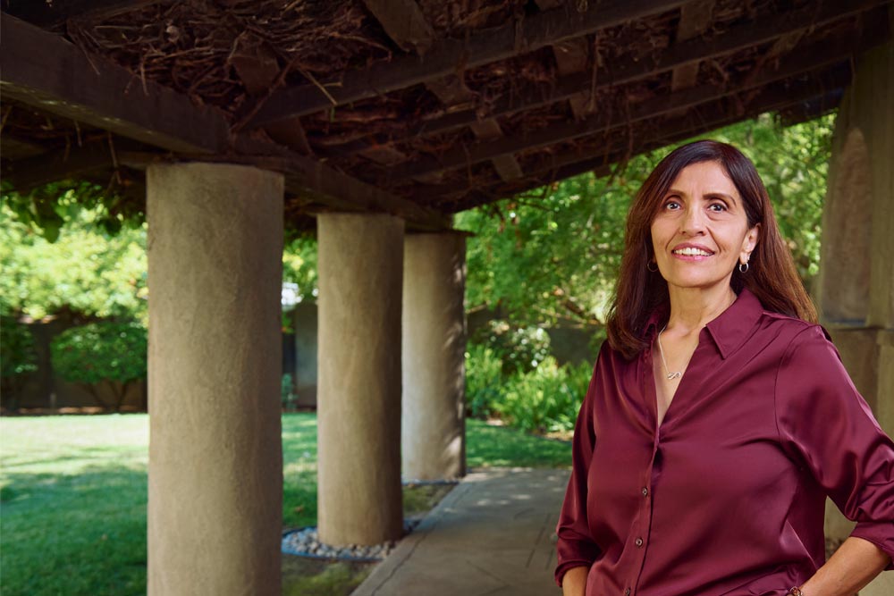 Claudia Gonzales, a darkhaired woman in late middle age, wears a wine-colored blouse beside a column